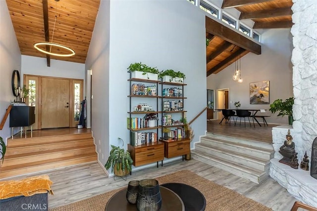 interior space with wooden ceiling, wood finished floors, high vaulted ceiling, beam ceiling, and stairs