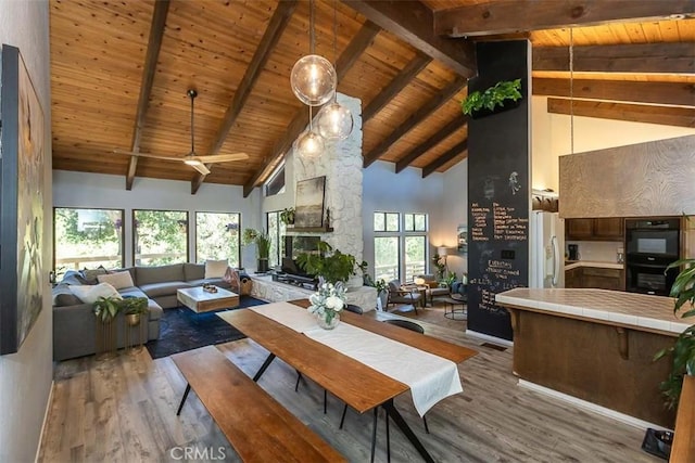 dining room featuring wood finished floors, wooden ceiling, high vaulted ceiling, beamed ceiling, and ceiling fan