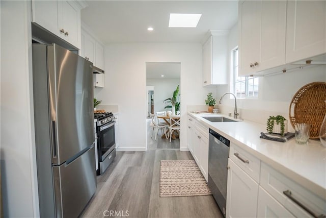 4110 E Vermont St, Long Beach, CA 90814 - kitchen with stainless steel appliances, a sink, wood finished floors, a skylight, and light countertops