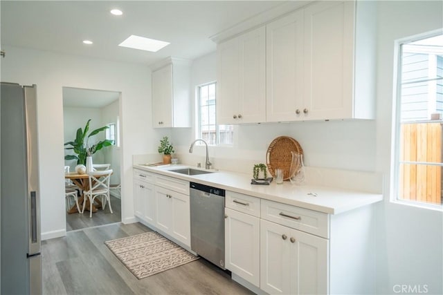 4110 E Vermont St, Long Beach, CA 90814 - kitchen with stainless steel appliances, a sink, light wood-style floors, white cabinets, and light countertops