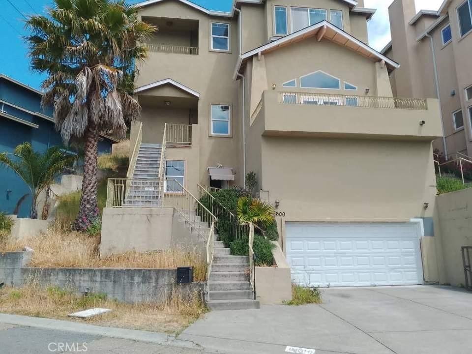 8600 Thermal St, Oakland, CA 94605 - view of front of property featuring stairway, stucco siding, a garage, and driveway