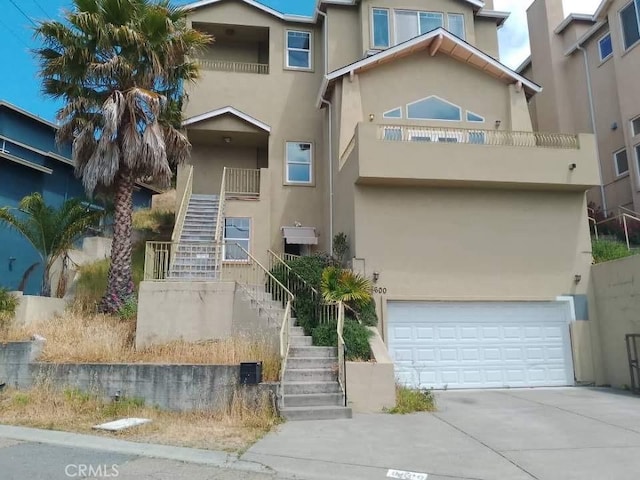 8600 Thermal St, Oakland, CA 94605 - view of front of property featuring stairway, stucco siding, a garage, and driveway