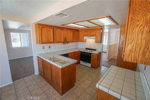 14410 Navajo Rd, Apple Valley, CA 92307 - kitchen with white gas range oven, under cabinet range hood, tile counters, a peninsula, and a sink