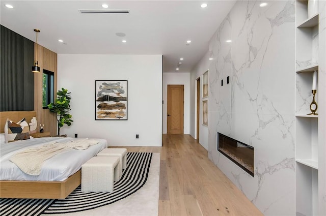 5132 Lindley Ave, Encino, CA 91316 - bedroom with light wood-style floors, recessed lighting, a fireplace, and an accent wall