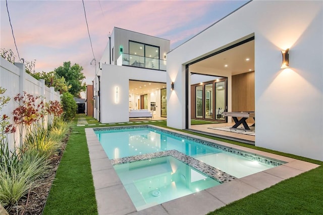 5132 Lindley Ave, Encino, CA 91316 - back of house at dusk featuring stucco siding, a patio area, fence, and a pool with connected hot tub