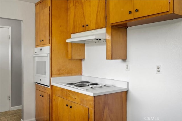 2880 Foothill Blvd, Oroville, CA 95966 - kitchen with white appliances, under cabinet range hood, light countertops, and brown cabinetry