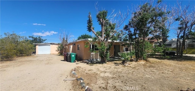 7067 Tamarisk Ave, Yucca Valley, CA 92284 - view of front of home featuring dirt driveway, a detached garage, and stucco siding