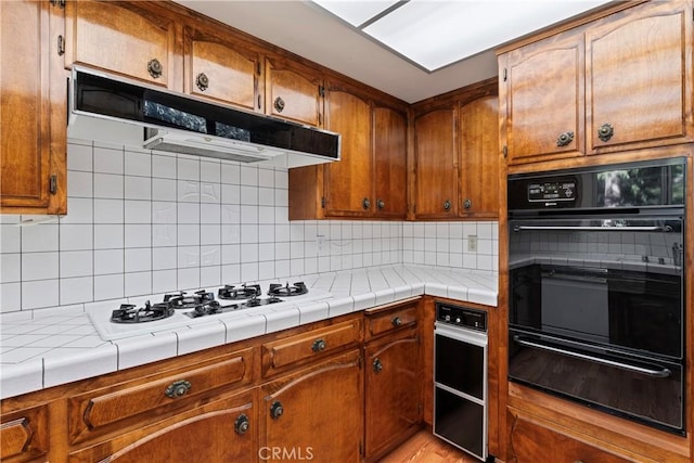 300 Pioneer Rd, Lake Arrowhead, CA 92352 - kitchen with a warming drawer, under cabinet range hood, black oven, white gas cooktop, and brown cabinets