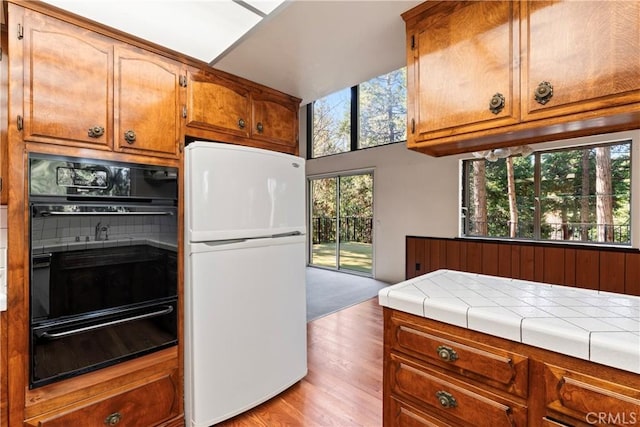 300 Pioneer Rd, Lake Arrowhead, CA 92352 - kitchen with freestanding refrigerator, a warming drawer, oven, brown cabinetry, and light wood finished floors