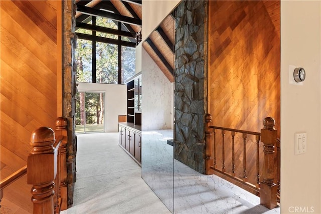 300 Pioneer Rd, Lake Arrowhead, CA 92352 - hall featuring carpet flooring, a towering ceiling, wooden walls, beamed ceiling, and an upstairs landing