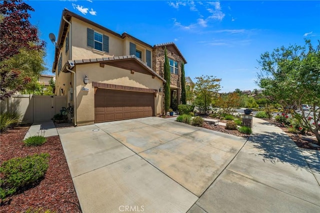 view of front of home featuring stucco siding, driveway, a garage, fence, and a gate
