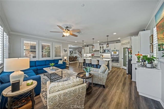 living room with a ceiling fan, dark wood finished floors, crown molding, recessed lighting, and stairs