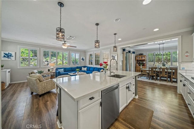 kitchen with a sink, stainless steel dishwasher, open floor plan, crown molding, and plenty of natural light