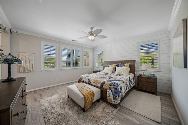 bedroom featuring multiple windows, crown molding, wood finished floors, baseboards, and a ceiling fan