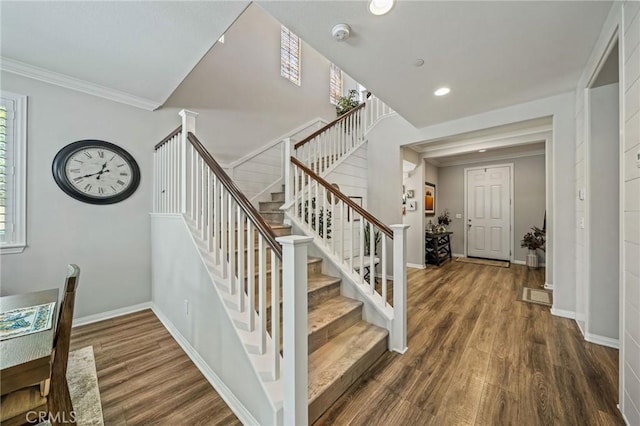 staircase featuring wood finished floors, plenty of natural light, baseboards, recessed lighting, and ornamental molding
