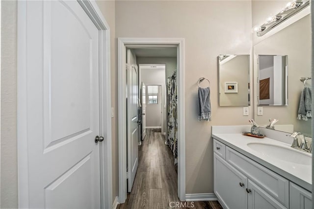 full bathroom with wood finished floors, baseboards, and vanity