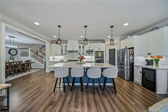 kitchen featuring appliances with stainless steel finishes, wine cooler, light countertops, ornamental molding, and dark wood-style floors