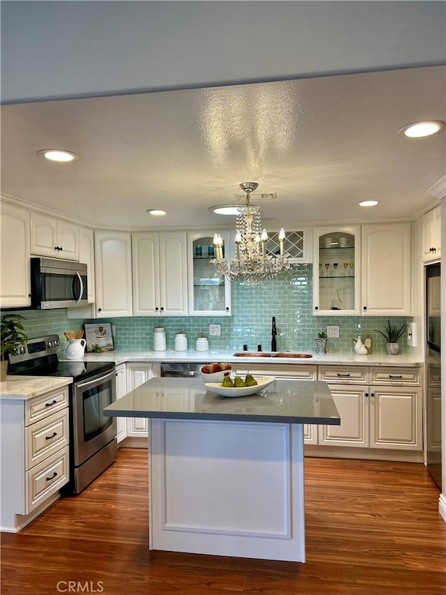 kitchen with stainless steel appliances, a sink, glass insert cabinets, decorative backsplash, and recessed lighting