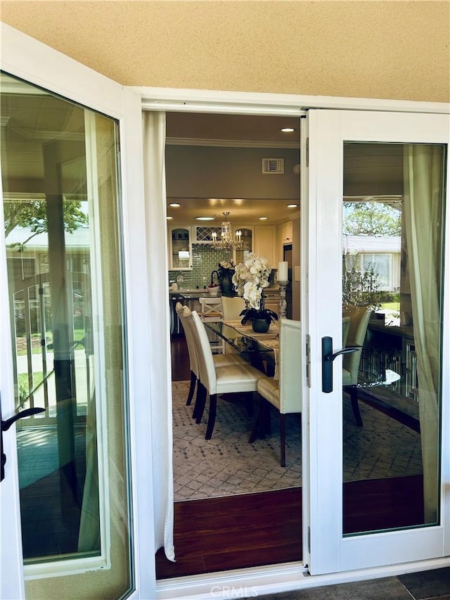 exterior space with wood finished floors, ornamental molding, and a chandelier