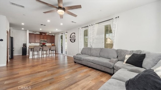 living area with ceiling fan, recessed lighting, light wood-type flooring, and baseboards