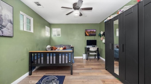 bedroom with light wood-style flooring, baseboards, an office area, and ceiling fan