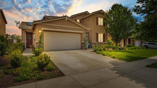 craftsman-style home with an attached garage, roof mounted solar panels, a yard, driveway, and stone siding