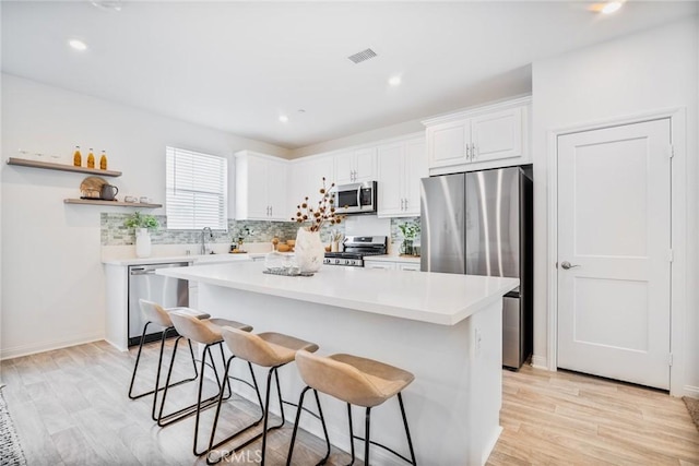 1609 Fig Tree Way, Oceanside, CA 92056 - kitchen with appliances with stainless steel finishes, a breakfast bar, open shelves, white cabinetry, and recessed lighting