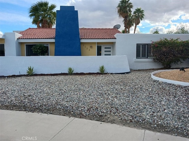 1123 E El Cid E, El Cid, Palm Springs, CA 92262 - view of front of house featuring a fenced front yard, a chimney, a tiled roof, and stucco siding
