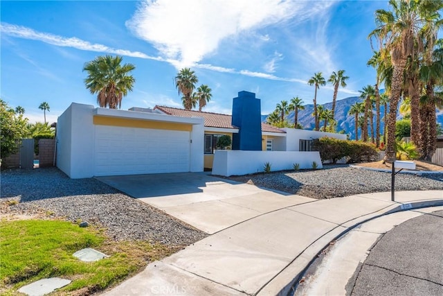 1123 E El Cid E, El Cid, Palm Springs, CA 92262 - mediterranean / spanish home featuring an attached garage, concrete driveway, stucco siding, and a chimney