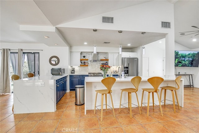 1123 E El Cid E, El Cid, Palm Springs, CA 92262 - kitchen featuring appliances with stainless steel finishes, blue cabinetry, open shelves, decorative backsplash, and a peninsula