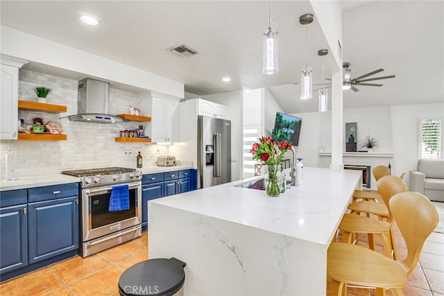 1123 E El Cid E, El Cid, Palm Springs, CA 92262 - kitchen with stainless steel appliances, blue cabinets, open shelves, wall chimney range hood, and lofted ceiling