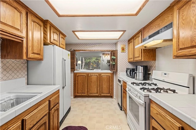 1513 Bernina Dr, Pine Mountain Club, CA 93222 - kitchen featuring white appliances, under cabinet range hood, brown cabinets, and tile counters