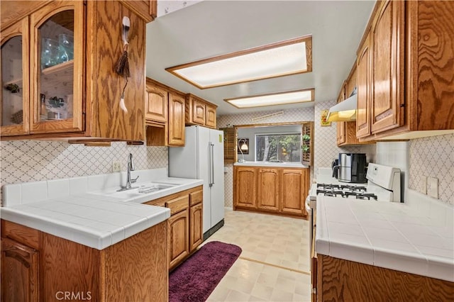 1513 Bernina Dr, Pine Mountain Club, CA 93222 - kitchen with under cabinet range hood, white appliances, brown cabinets, wallpapered walls, and light flooring