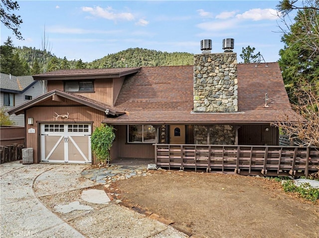 1513 Bernina Dr, Pine Mountain Club, CA 93222 - view of front facade with a garage, driveway, a chimney, roof with shingles, and covered porch