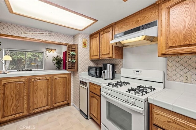 1513 Bernina Dr, Pine Mountain Club, CA 93222 - kitchen featuring white gas range, under cabinet range hood, brown cabinets, black microwave, and wallpapered walls