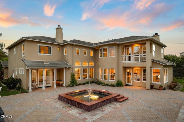 181 Via Sandra, Newbury Park, CA 91320 - back of house at dusk with a chimney, a patio, stucco siding, an outdoor fire pit, and a balcony