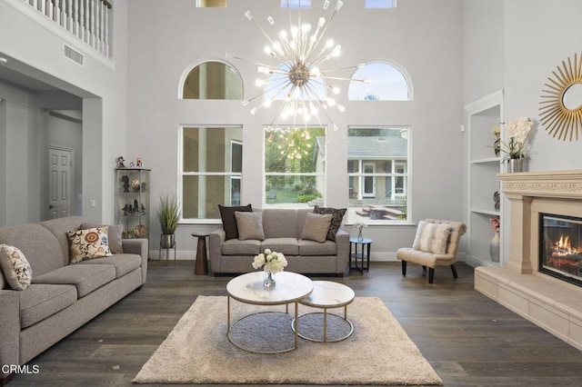 181 Via Sandra, Newbury Park, CA 91320 - living area featuring a towering ceiling, a glass covered fireplace, dark wood finished floors, built in shelves, and baseboards