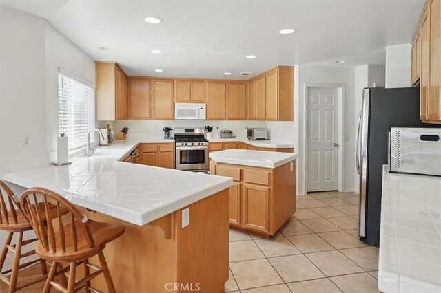 28652 Deer Springs Dr, Saugus, CA 91390 - kitchen featuring white microwave, stainless steel gas range oven, a peninsula, a sink, and tile countertops