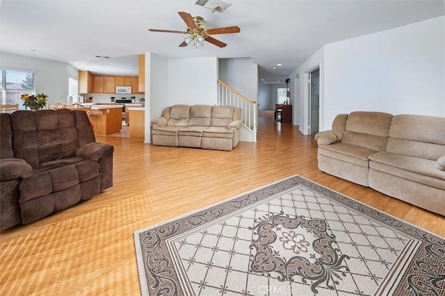 28652 Deer Springs Dr, Saugus, CA 91390 - living room featuring light wood finished floors, stairway, and a ceiling fan