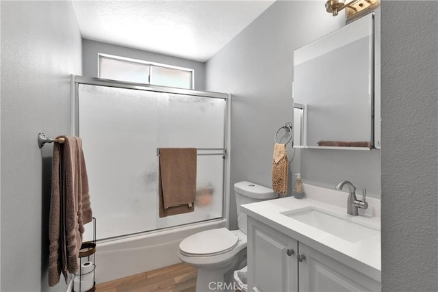 15074 Willow St, Hesperia, CA 92345 - full bathroom featuring wood finished floors, bath / shower combo with glass door, vanity, and toilet