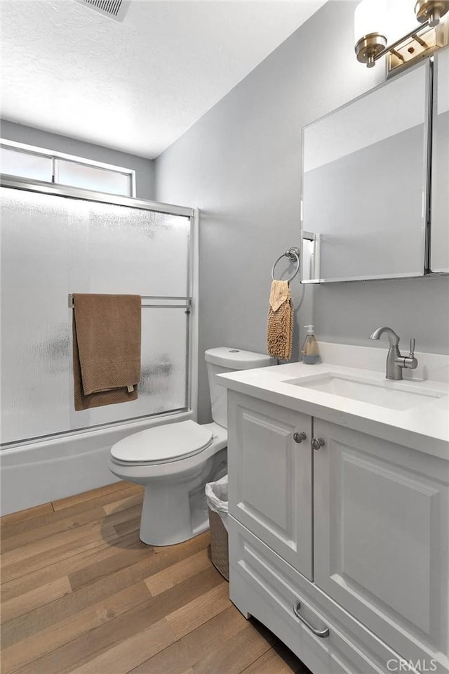 15074 Willow St, Hesperia, CA 92345 - bathroom featuring wood finished floors, combined bath / shower with glass door, toilet, and vanity