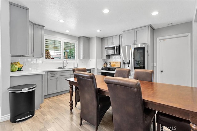 15074 Willow St, Hesperia, CA 92345 - kitchen featuring gray cabinets, appliances with stainless steel finishes, a sink, light wood-style floors, and backsplash