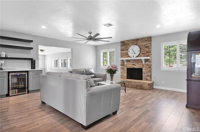 15074 Willow St, Hesperia, CA 92345 - living area with beverage cooler, a ceiling fan, plenty of natural light, a textured ceiling, and a stone fireplace