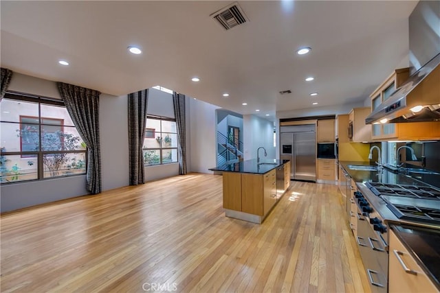 143 Union Jack Mall, Marina Del Rey, CA 90292 - kitchen with appliances with stainless steel finishes, dark countertops, a sink, light wood-style flooring, and wall chimney exhaust hood