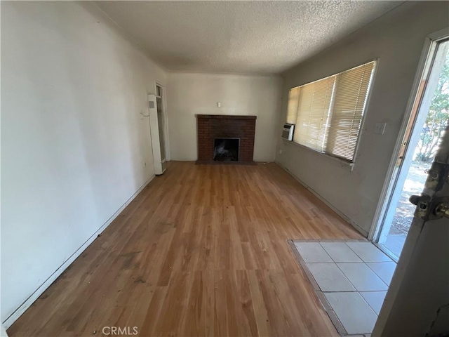 4004 N 3rd Ave, San Bernardino, CA 92407 - unfurnished living room featuring light wood-type flooring, a textured ceiling, and a brick fireplace