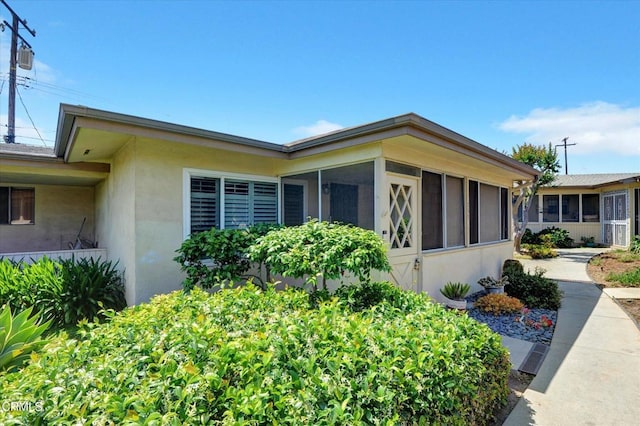 view of side of home featuring stucco siding and a sunroom