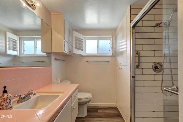 full bathroom with a stall shower, toilet, wood finished floors, and healthy amount of natural light