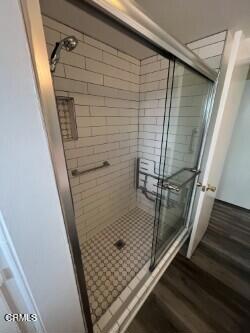 bathroom with a stall shower and wood finished floors