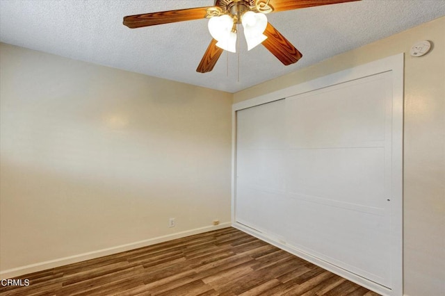 unfurnished bedroom featuring wood finished floors, baseboards, a closet, a ceiling fan, and a textured ceiling