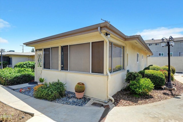 view of home's exterior with stucco siding and a sunroom